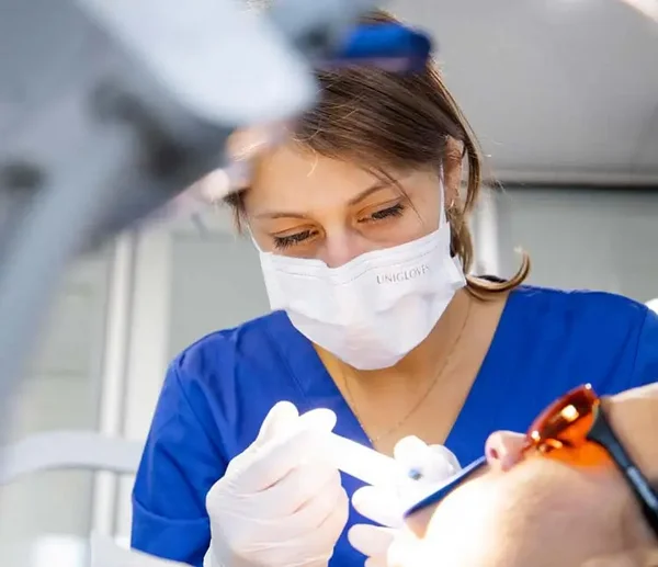 Prophylaxeassistentin trägt Bleachinggel bei einem Patienten auf
