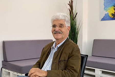 Älterer Herr mit Brille sitzt in Wartebereich